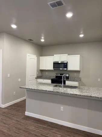 a view of a kitchen with granite countertop cabinets a sink and a wooden floor