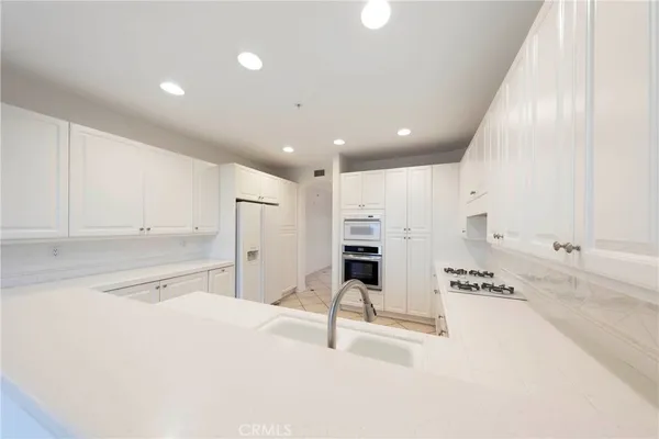 a kitchen with stainless steel appliances kitchen island sink refrigerator and cabinets