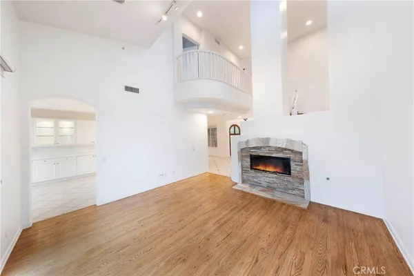 an empty room with wooden floor fireplace and windows