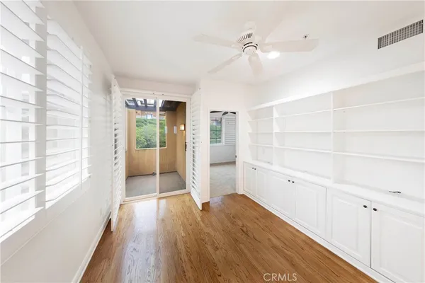 a view of empty room with wooden floor and fan