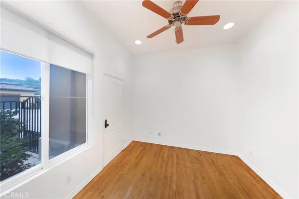 a view of a room with wooden floor and a ceiling fan