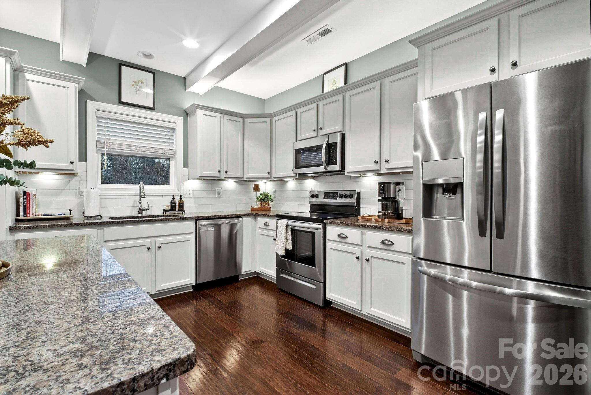 9092 Pitcairn Drive Fort Mill, SC 29708 - Photo 16 of 47 a kitchen with stainless steel appliances granite countertop a refrigerator a stove a sink dishwasher a microwave oven with white cabinets and wooden floor