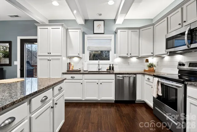 a kitchen with stainless steel appliances granite countertop a stove a sink and white cabinets