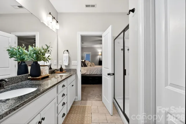 a en suite bathroom with a granite countertop sink and a mirror