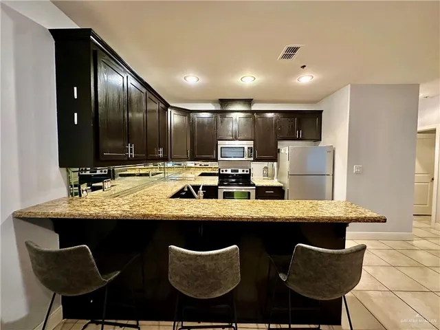 a kitchen with stainless steel appliances granite countertop a table chairs sink refrigerator and microwave