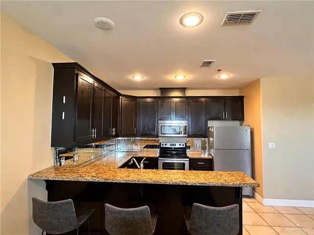 a kitchen with stainless steel appliances granite countertop a sink refrigerator and microwave