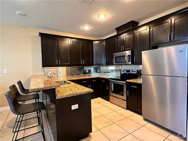 a kitchen with stainless steel appliances granite countertop a refrigerator a stove a sink and a microwave