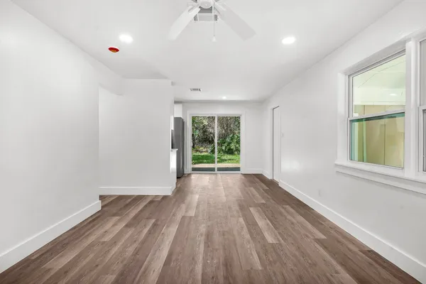 an empty room with wooden floor fan and windows