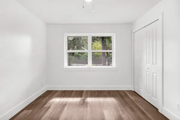 a view of an empty room with wooden floor and a window