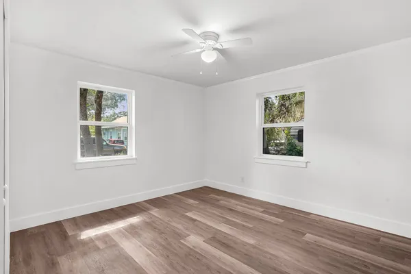an empty room with wooden floor and windows