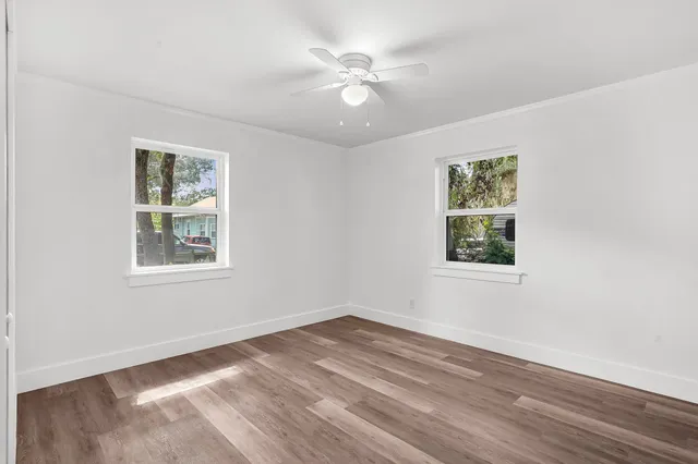 an empty room with wooden floor and windows
