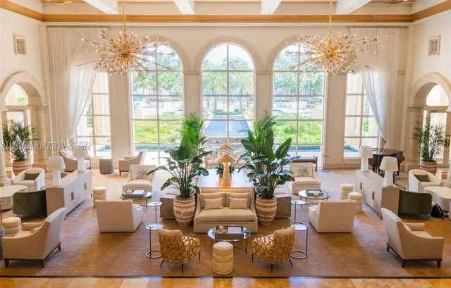 a living room with patio furniture and floor to ceiling windows