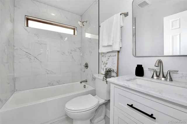 a bathroom with a granite countertop sink a toilet and shower