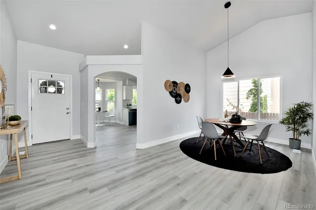 a view of a livingroom and a dining room with wooden floor a chandelier