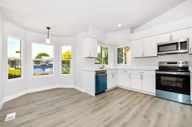 a kitchen with stainless steel appliances a stove top oven a sink a counter space and cabinets