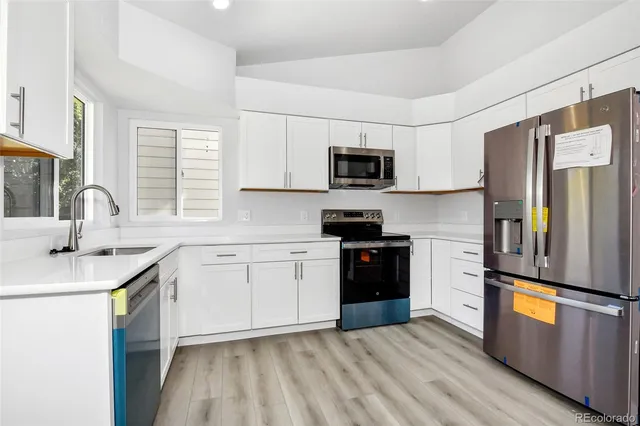 a kitchen with stainless steel appliances a sink cabinets and a window