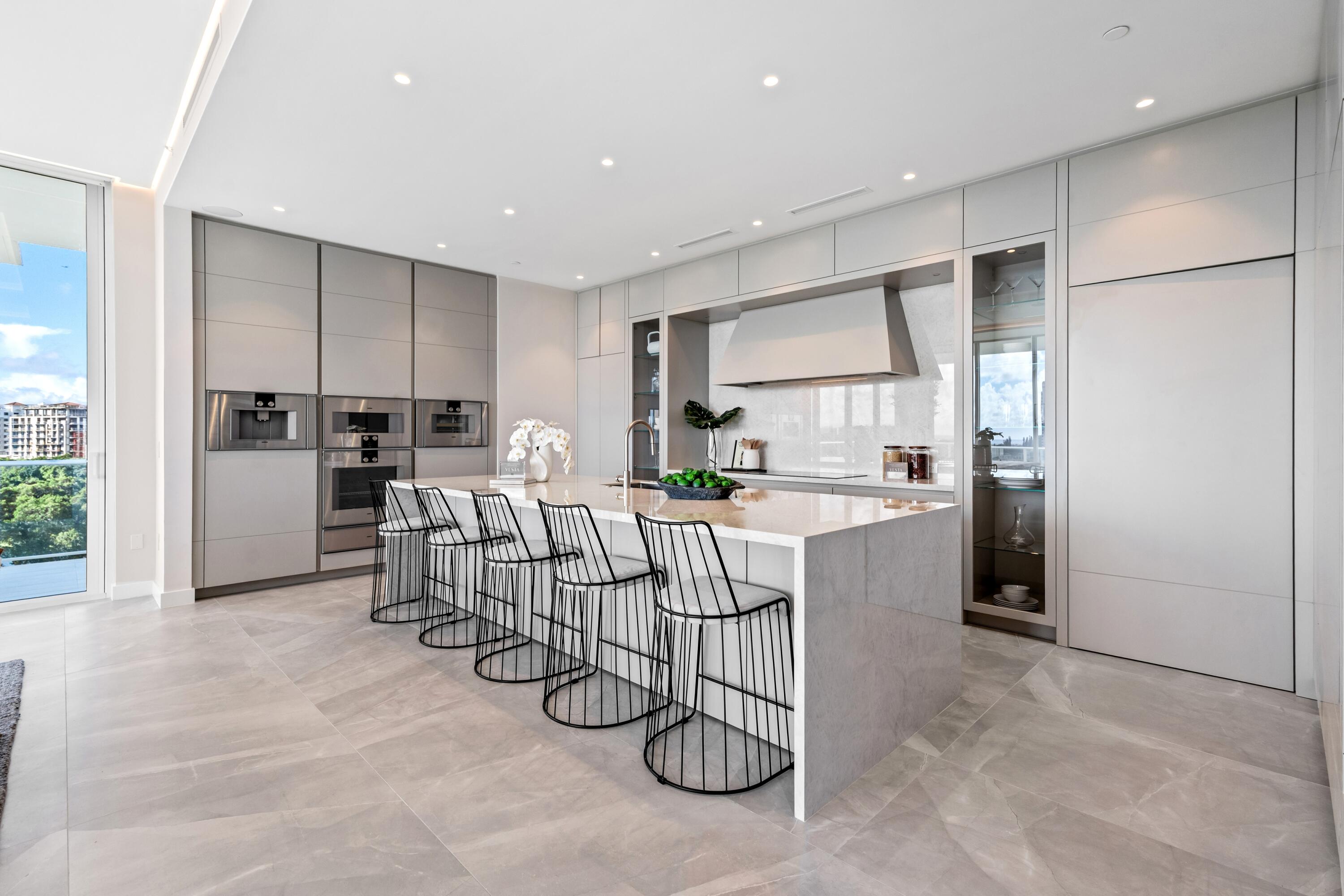 220 Southeast Mizner Boulevard, Unit PH24 Boca Raton, FL 33432 - Photo 11 of 51 a kitchen with a table chairs refrigerator and microwave