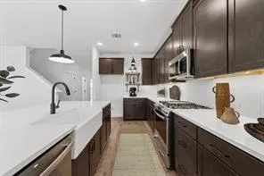 a kitchen with stainless steel appliances granite countertop a sink a stove and a wooden floors