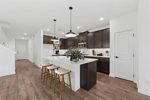 a kitchen with kitchen island a stove a refrigerator and a dining table with wooden floor