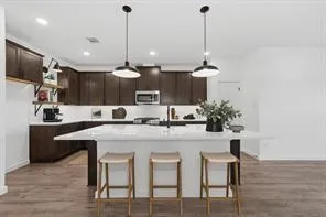 a kitchen with kitchen island a dining table chairs sink and cabinets