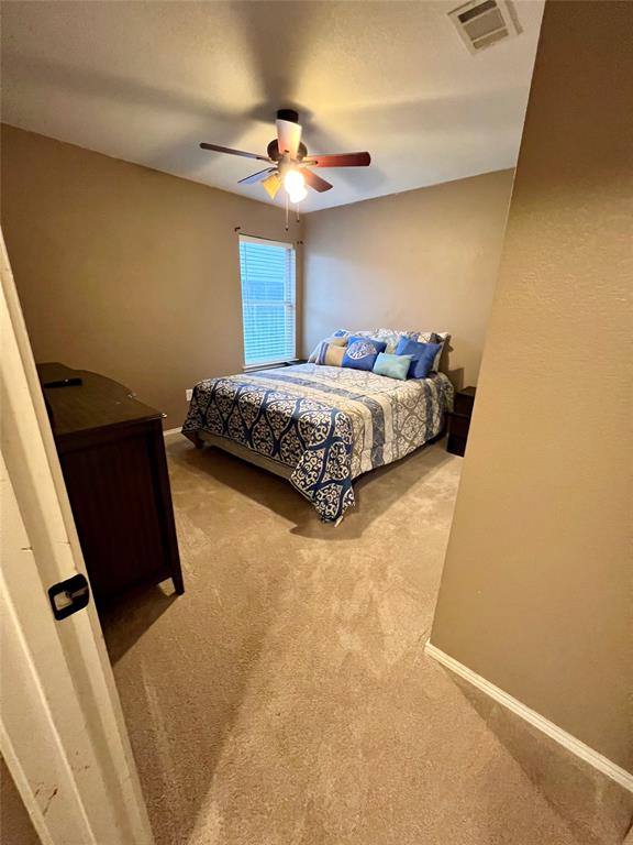 12201 Rolling Ridge Drive Fort Worth, TX 76028 - Photo 16 of 21 Warm-toned wall paint throughout, featuring a ceiling fan with light fixture, a window with horizontal blinds, and beige carpeting
