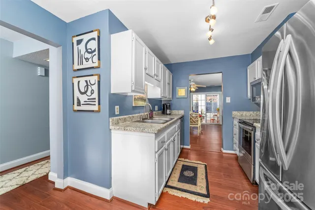 a kitchen with stainless steel appliances granite countertop a refrigerator a stove and a sink