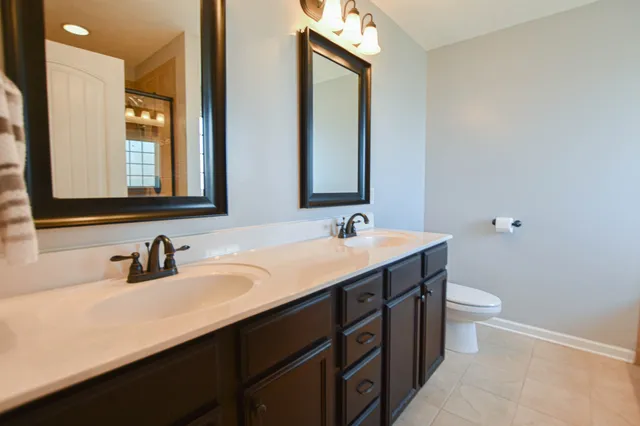 a bathroom with a double vanity sink toilet and mirror