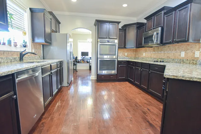 a kitchen with stainless steel appliances granite countertop wooden cabinets a stove top oven a sink and dishwasher