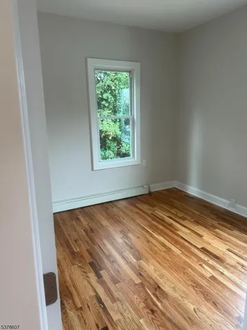 an empty room with wooden floor and window