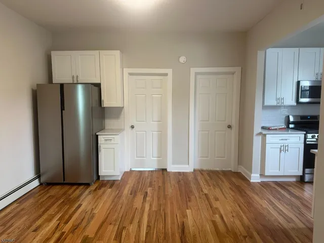 a view of kitchen with stainless steel appliances wooden floor and cabinets
