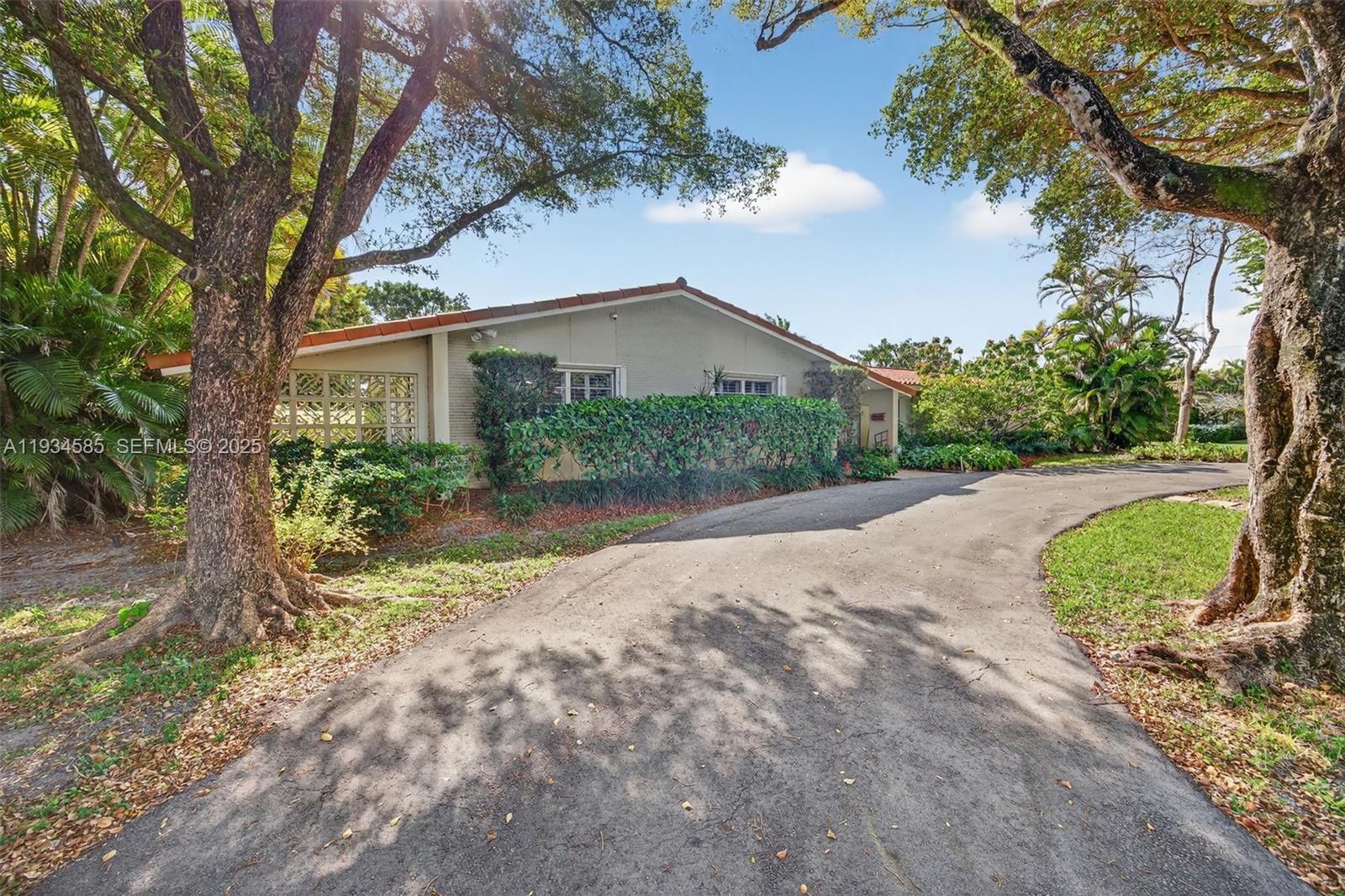 7300 Southwest 116th Terrace Pinecrest, FL 33156 - Photo 2 of 63 a view of a house with a small yard plants and a large tree