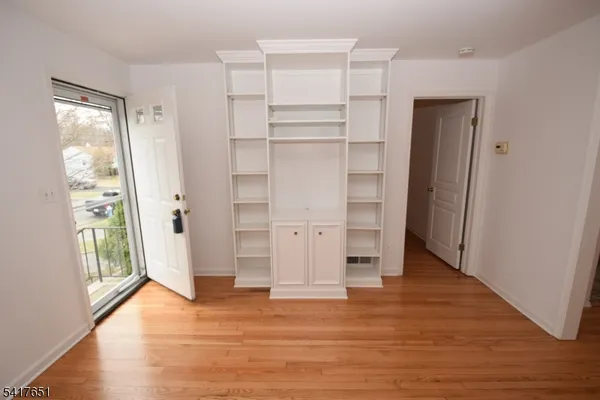 a view of empty room with wooden floor and entryway