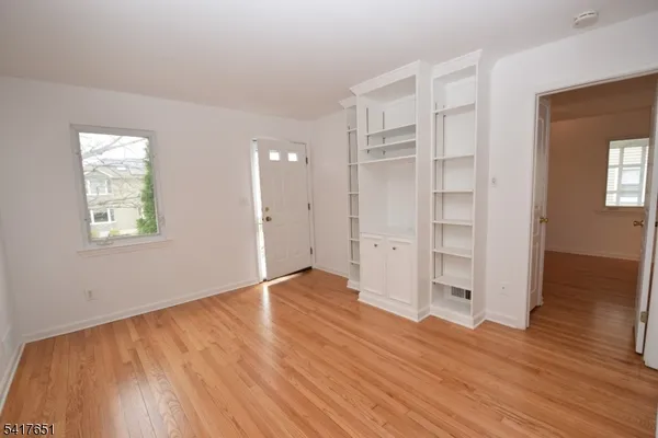an empty room with wooden floor closet and windows