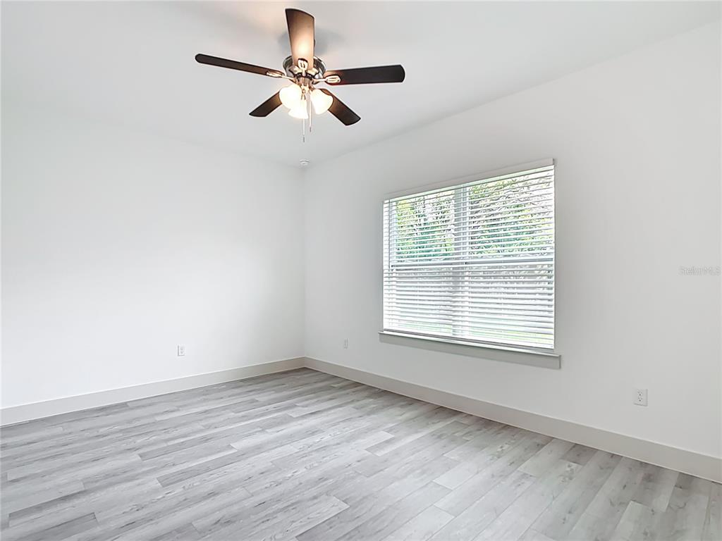 3525 Southwest 163rd Pl Road Ocala, FL 34473 - Photo 18 of 80 an empty room with wooden floor fan and windows
