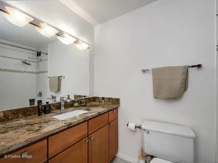 a bathroom with a granite countertop sink a toilet and a mirror
