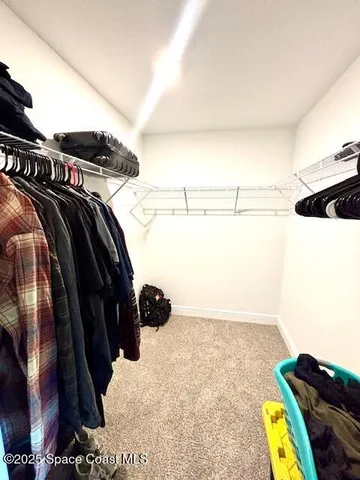 a view of walk in closet with clothes and shoes