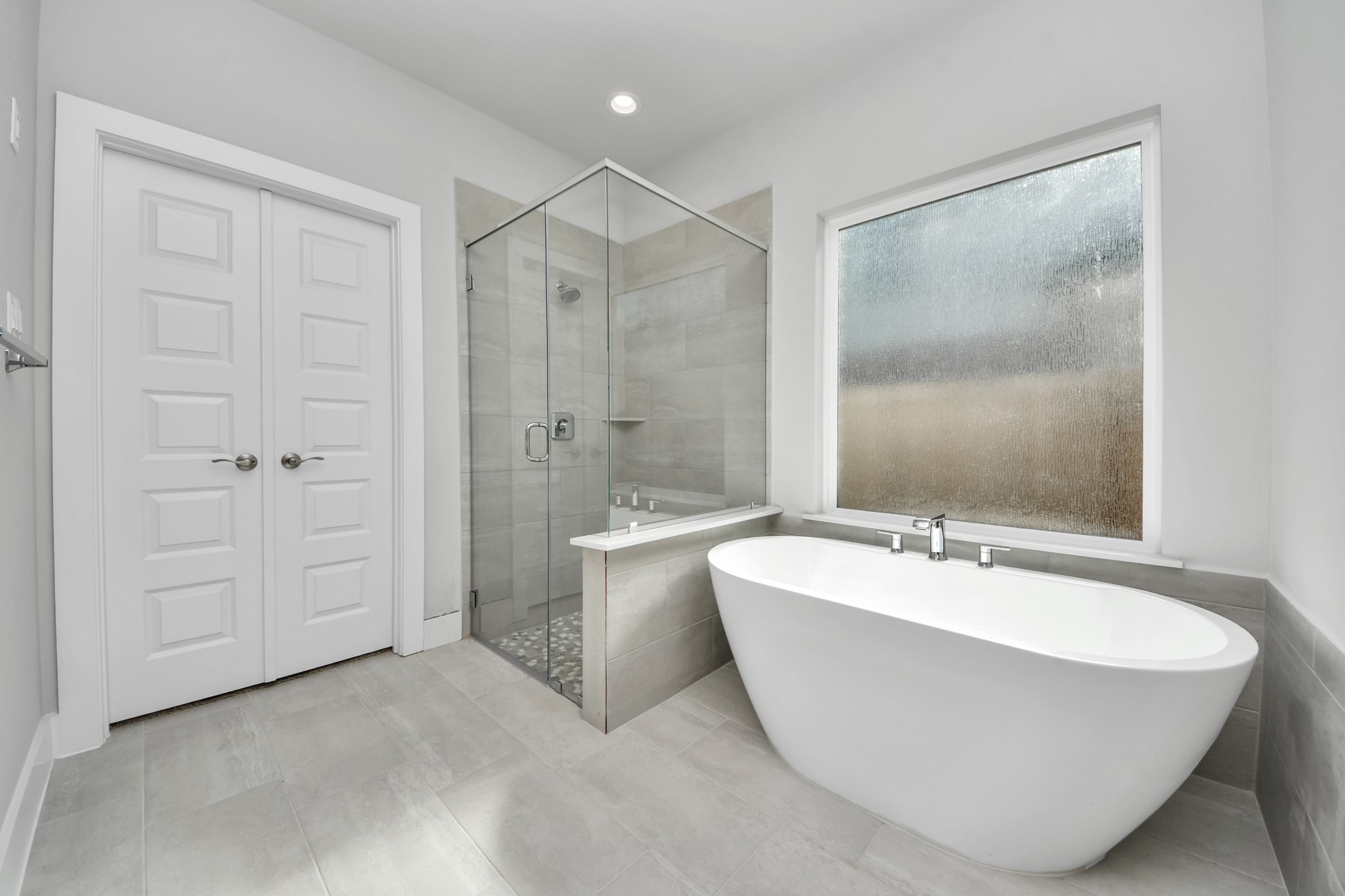 3102 Native Spg Drive Spring, TX 77373 - Photo 24 of 40 Escape to a spa-like oasis in this primary bathroom. Enjoy a walk-in shower with tile surround, a separate garden tub with custom detailing, and an elegant vanity featuring light countertops, modern hardware, and beautiful vanity lights. Experience luxury and relaxation in every detail. Sample photo of completed home with similar floor plan. Actual colors and selections may vary.