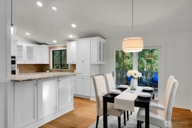 a kitchen with stainless steel appliances granite countertop a sink a stove a refrigerator white cabinets with wooden floor