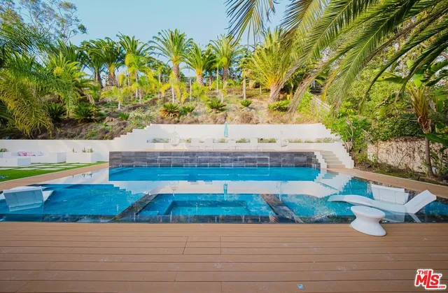 a large white kitchen with stainless steel appliances kitchen island granite countertop a refrigerator and a stove