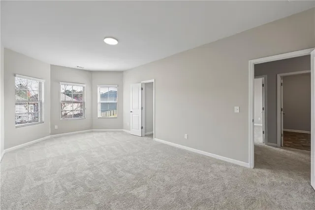 an empty room with a chandelier fan and windows