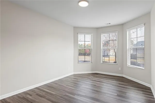 a view of an empty room with window and wooden floor