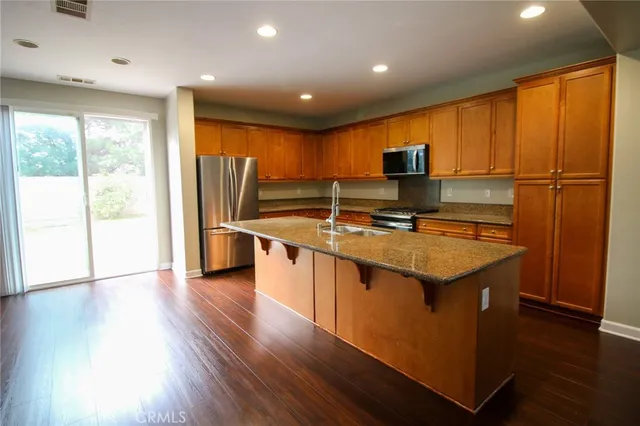 a kitchen with stainless steel appliances granite countertop a sink a stove and a refrigerator