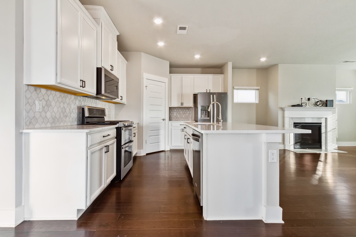 3261 Longstalk Road Antioch, TN 37013 - Photo 4 of 46 a kitchen with stainless steel appliances kitchen island granite countertop a stove top oven a sink a refrigerator white cabinets and wooden floor