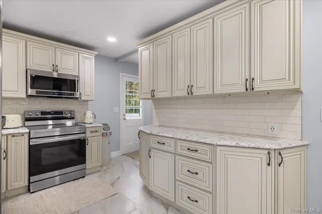 a kitchen with granite countertop white cabinets and stainless steel appliances