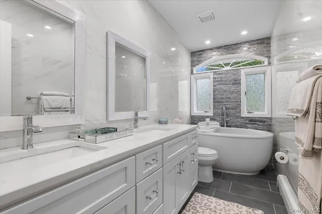 a bathroom with a double vanity sink toilet mirror and bathtub
