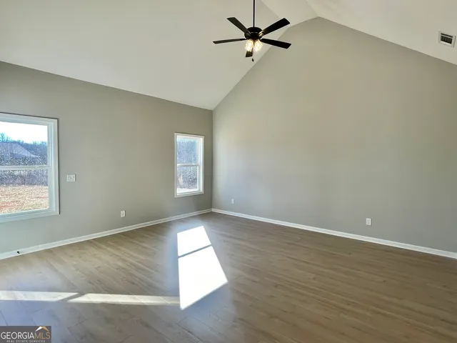 an empty room with wooden floor fan and windows