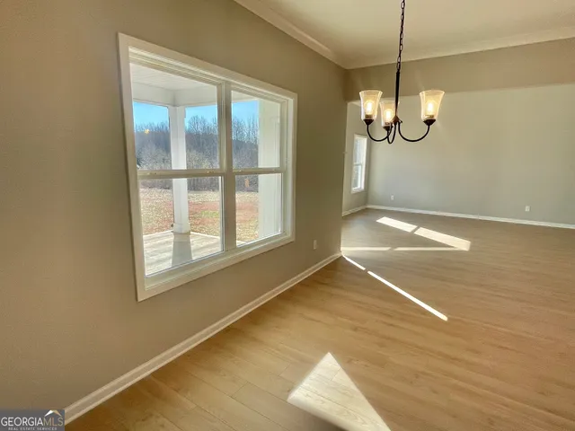 a view of empty room with wooden floor and window