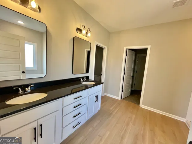 a bathroom with a granite countertop double vanity sink and mirror