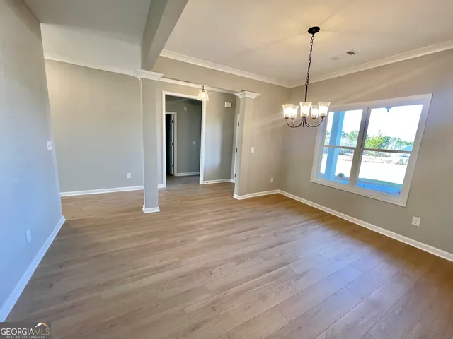 a view of an empty room with wooden floor fireplace and a window