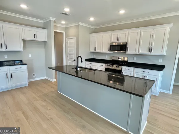 a large kitchen with stainless steel appliances granite countertop a stove a sink and a microwave